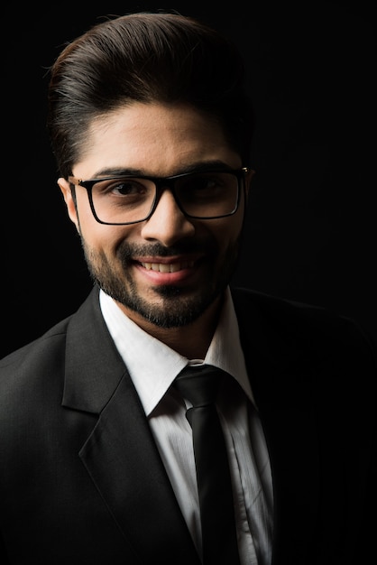 Portrait de jeune homme d'affaires indien barbu sur fond noir, éclairage de mauvaise humeur
