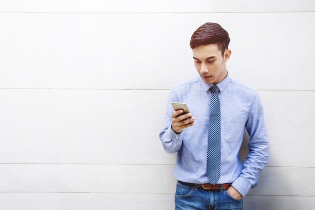 Portrait de jeune homme d&#39;affaires intelligent à l&#39;aide de smartphone au mur du bâtiment