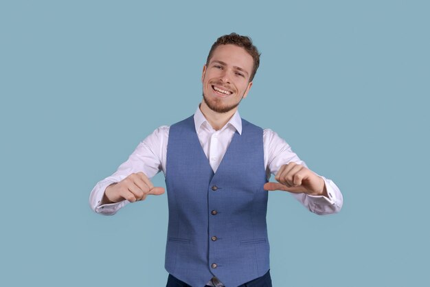 Portrait jeune homme d'affaires pointant ses doigts vers le bas isolé sur bleu