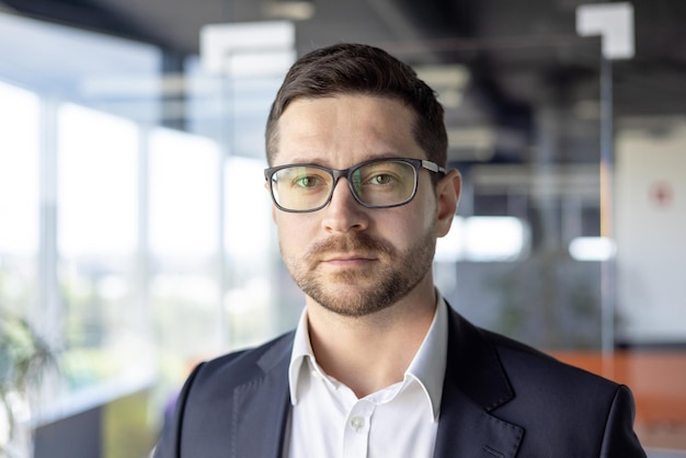 Portrait d'un jeune homme d'affaires sérieux et prospère, courtier, homme d'affaires, gros plan dans des verres et des affaires