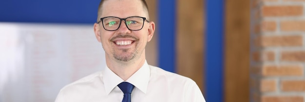 Portrait de jeune homme d'affaires souriant dans des verres au bureau