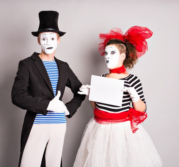 Portrait d'un jeune homme d'affaires souriant et heureux montrant une enseigne vierge, avec une zone de fond pour le texte ou le slogan, sur fond gris