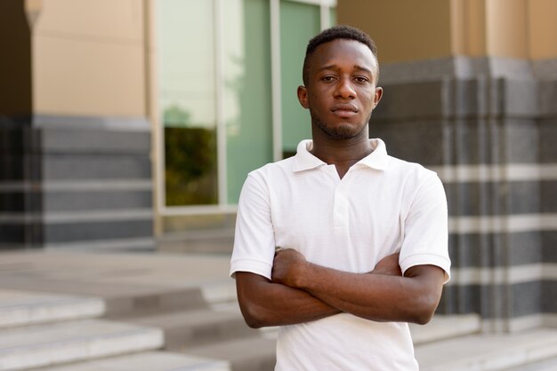 Portrait de jeune homme africain au bâtiment moderne dans la ville en plein air