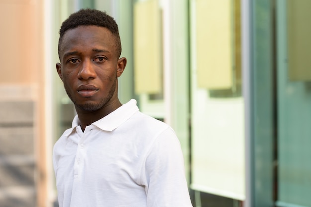 Portrait de jeune homme africain au bâtiment moderne dans la ville en plein air