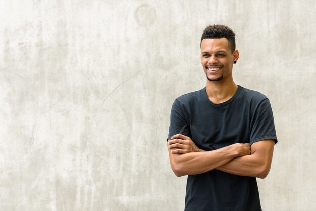 Portrait de jeune homme africain barbu beau contre le mur de béton à l'extérieur