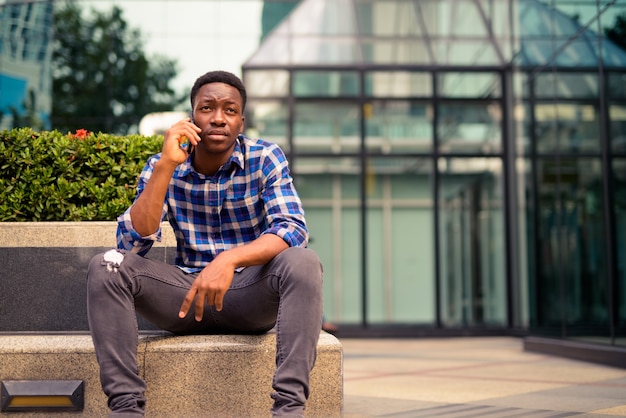 Portrait de jeune homme africain beau dans le parc de la ville en plein air