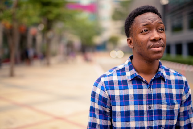 Portrait de jeune homme africain beau dans les rues de la ville à l'extérieur