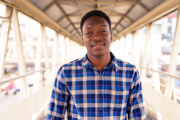 Portrait de jeune homme africain beau à la passerelle dans la ville en plein air