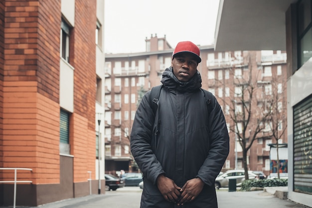 Portrait de jeune homme africain debout dans la rue et à la recherche de caméra