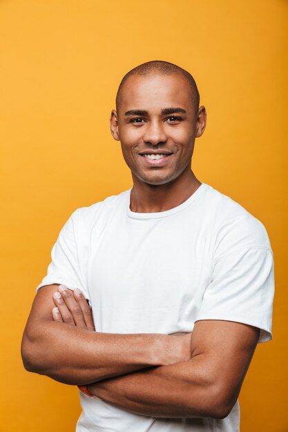 Portrait d'un jeune homme africain décontracté, souriant et confiant, debout sur un mur jaune