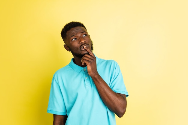 Portrait de jeune homme africain isolé sur fond de studio jaune avec espace pour copie