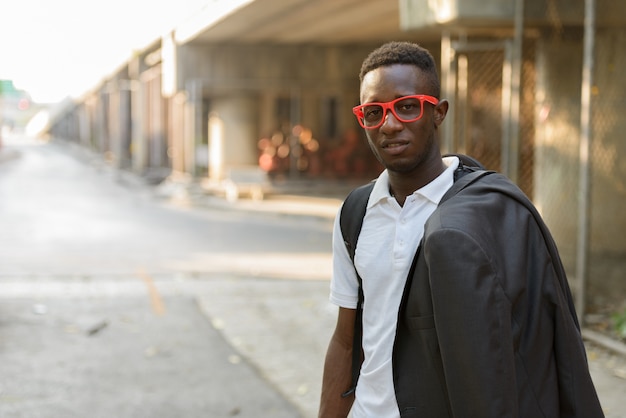 Portrait de jeune homme africain avec des lunettes dans les rues de la ville à l'extérieur