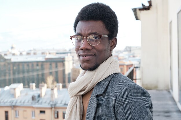 Portrait De Jeune Homme Africain à Lunettes Et En Vêtements Chauds Debout Sur Le Balcon