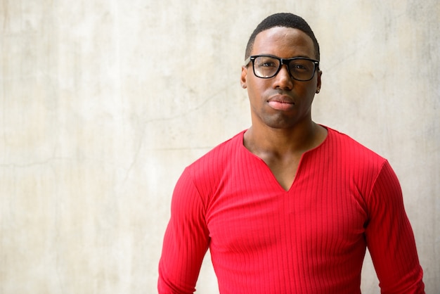 Portrait de jeune homme africain musclé beau avec des lunettes contre le mur de béton à l'extérieur