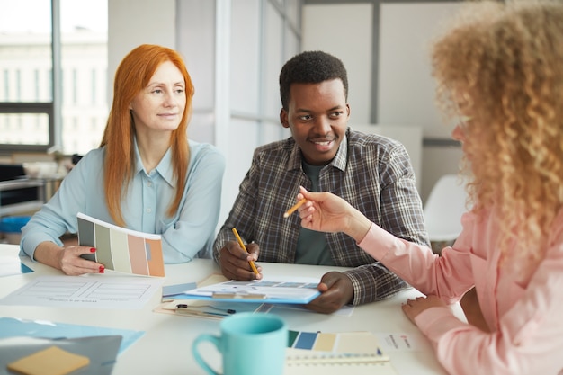 Portrait de jeune homme afro-américain discutant du projet créatif lors de la réunion avec l'équipe au bureau moderne, espace copie