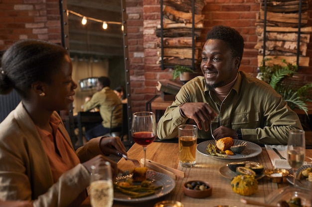 Portrait de jeune homme afro-américain souriant à girlfried tout en profitant d'un dîner en plein air