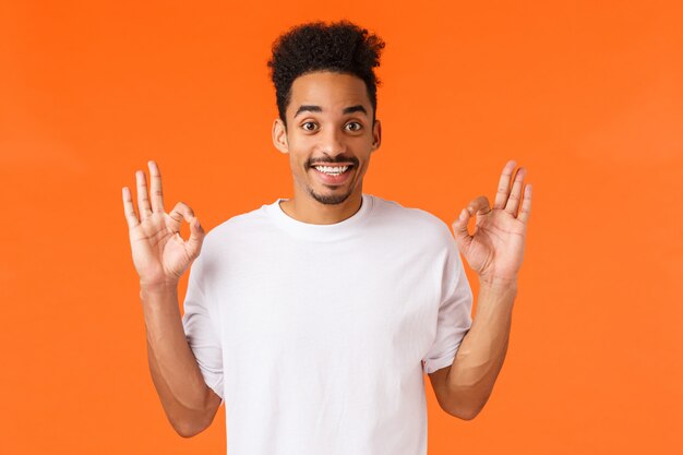 Portrait jeune homme afro-américain en t-shirt blanc montrant le geste.