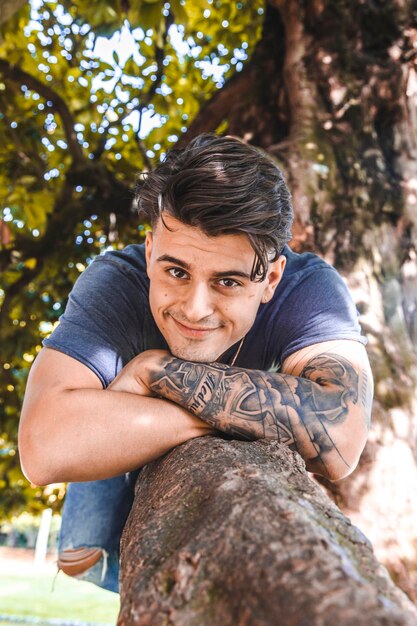 Portrait d'un jeune homme allongé sur un arbre