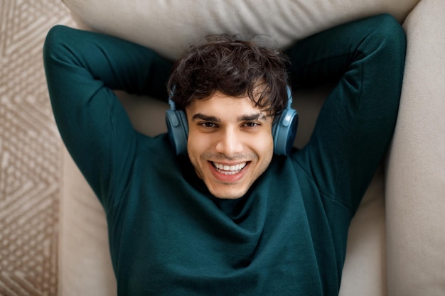 Portrait d'un jeune homme arabe heureux avec des écouteurs sans fil qui profite du confort musical préféré et du temps libre