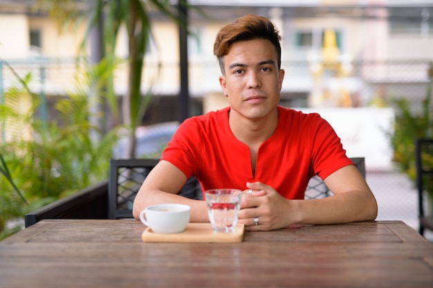 Portrait de jeune homme asiatique au café en plein air