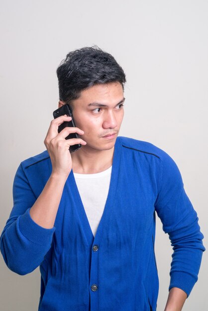 Portrait de jeune homme asiatique beau parler au téléphone