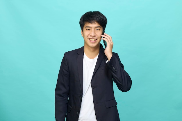 Portrait d'un jeune homme asiatique beau et souriant dans un costume semi-formel à l'aide d'un téléphone portable