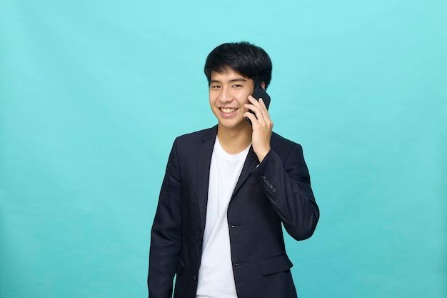 Portrait d'un jeune homme asiatique beau et souriant dans un costume semi-formel à l'aide d'un téléphone portable