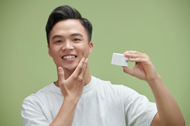 Portrait de jeune homme asiatique avec une bouteille de cosmétiques