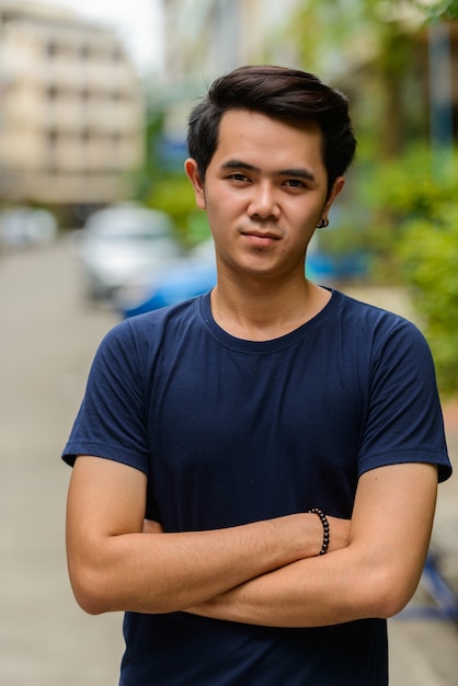 Portrait de jeune homme asiatique avec les bras croisés à l'extérieur
