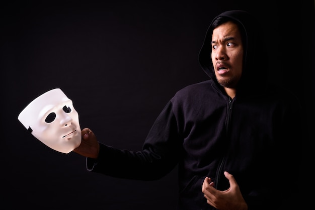 Portrait de jeune homme asiatique avec capuche et masque sur fond noir