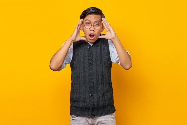 Portrait de jeune homme asiatique choqué regardant la caméra sur fond jaune