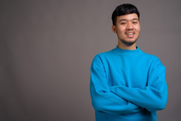 Portrait de jeune homme asiatique contre gris