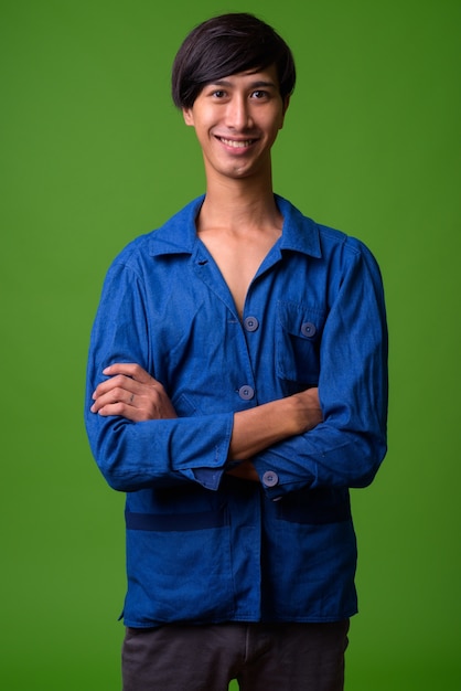 Portrait de jeune homme asiatique contre le mur vert