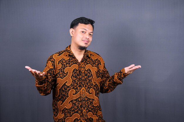 portrait de jeune homme asiatique dans un batik posant isolé sur fond gris