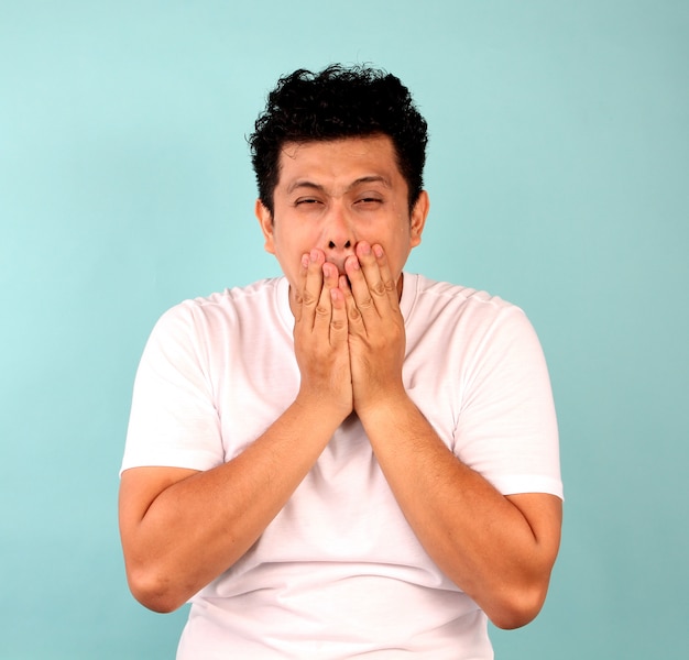 Portrait d'un jeune homme asiatique déçu, se concentrant sur les hommes en t-shirts blancs sur un bleu.