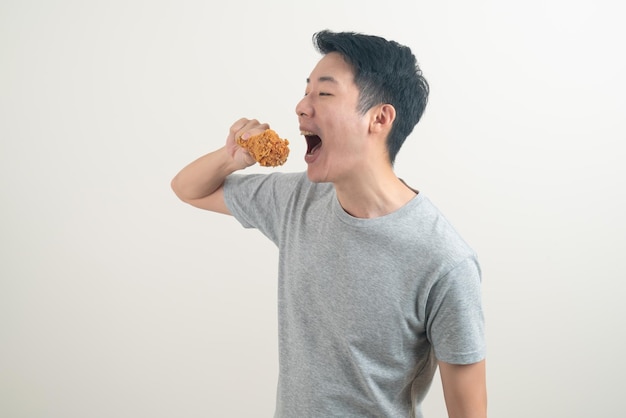 Portrait jeune homme asiatique avec du poulet frit à portée de main