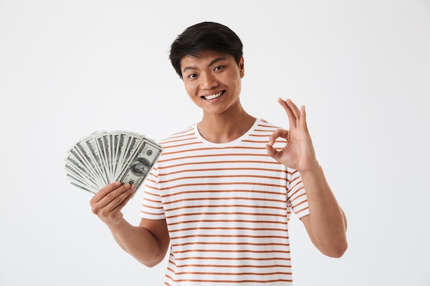 Portrait d'un jeune homme asiatique excité tenant de l'argent