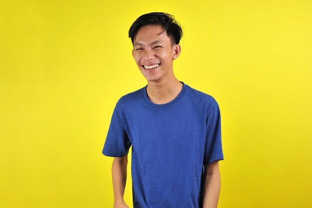 Portrait d'un jeune homme asiatique heureux souriant devant la caméra, isolé sur jaune