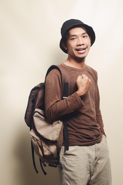 Portrait d'un jeune homme asiatique joyeux portant un chapeau noir et portant un sac à dos pour voyager