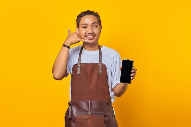 Portrait d'un jeune homme asiatique joyeux tenant un smartphone et faisant un geste de téléphone avec les mains