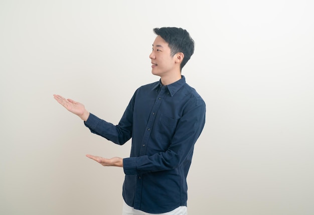 portrait jeune homme asiatique avec la main pointant ou présentant sur fond blanc