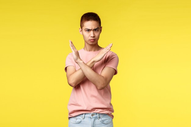 Portrait d'un jeune homme asiatique montrant le geste sur le mur jaune