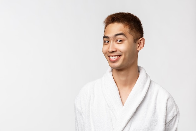 Portrait de jeune homme asiatique en peignoir montrant le geste. Après la douche