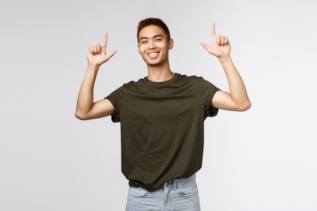 Portrait d'un jeune homme asiatique pointant vers le haut avec les doigts