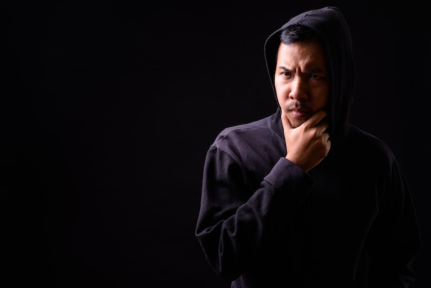 Portrait de jeune homme asiatique portant un sweat à capuche sur fond noir