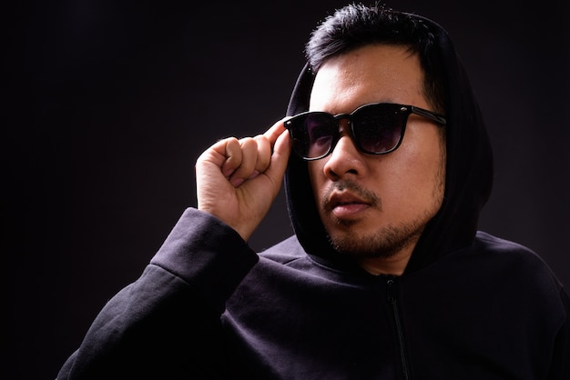 Portrait de jeune homme asiatique portant un sweat à capuche sur fond noir
