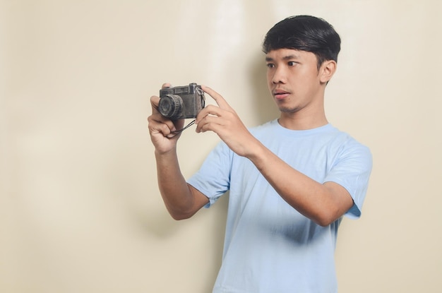 Portrait d'un jeune homme asiatique prenant une photo sur un fond isolé