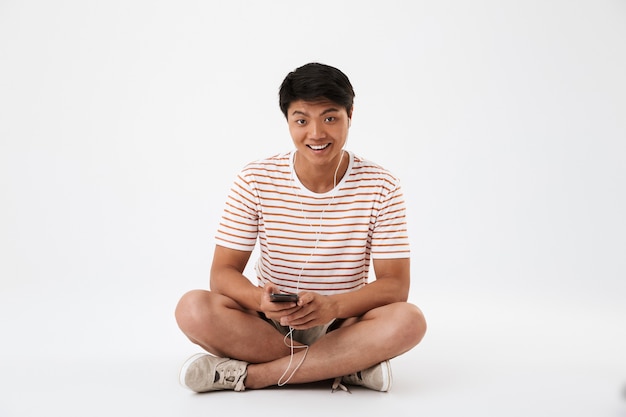 Portrait d'un jeune homme asiatique souriant, écouter de la musique