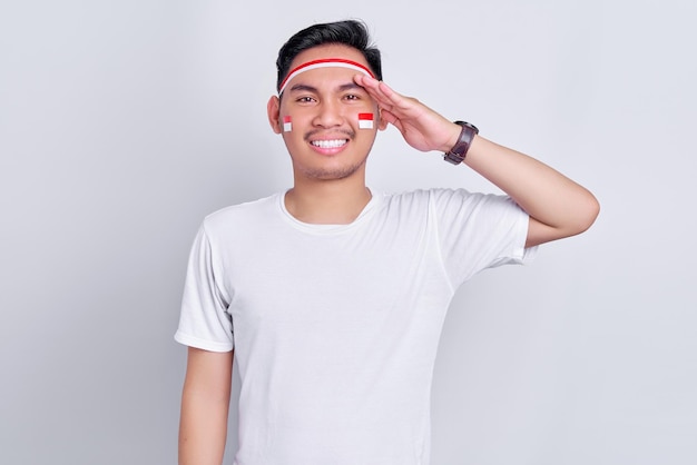 Portrait d'un jeune homme asiatique souriant montrant un geste de respect tout en célébrant le jour de l'indépendance indonésienne le 17 août isolé sur fond blanc