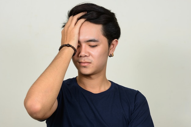 Portrait de jeune homme asiatique stressé ayant des maux de tête